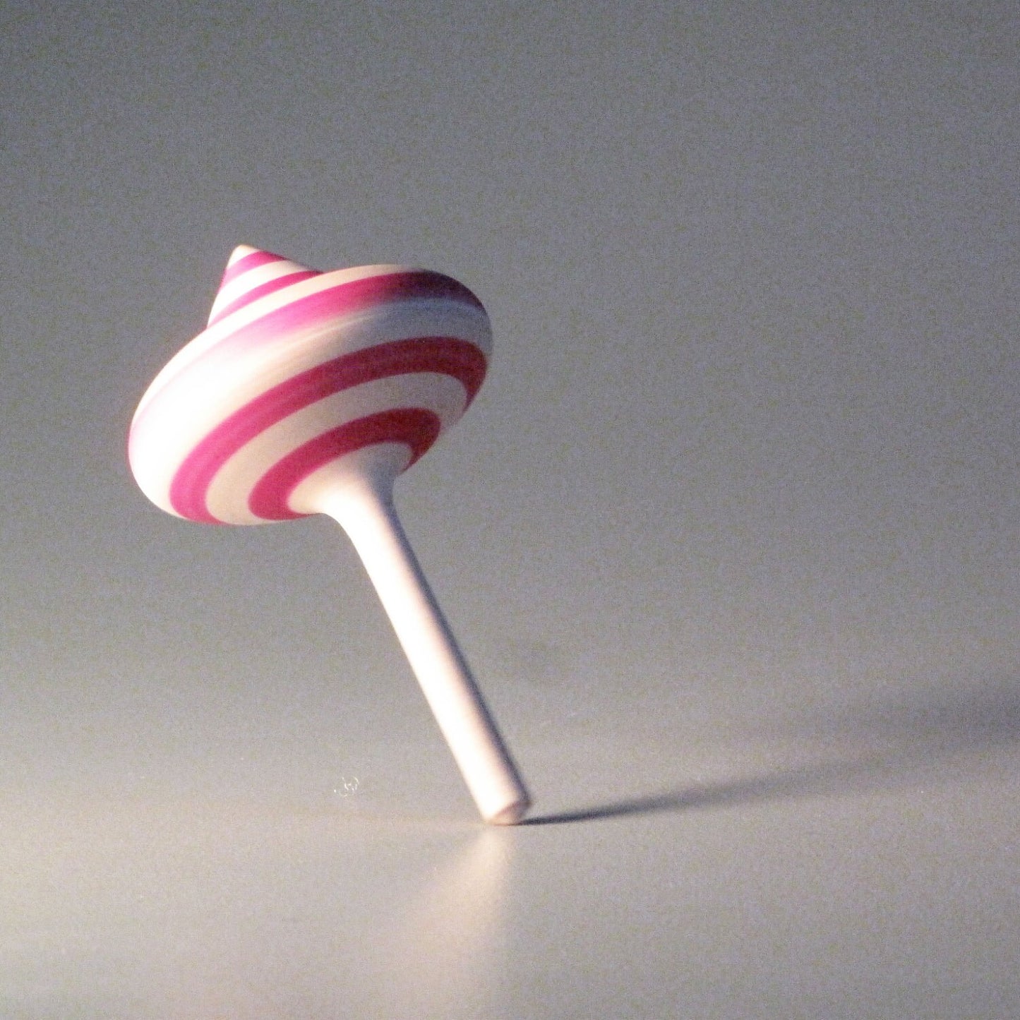 Toy spinning top with pink stripes