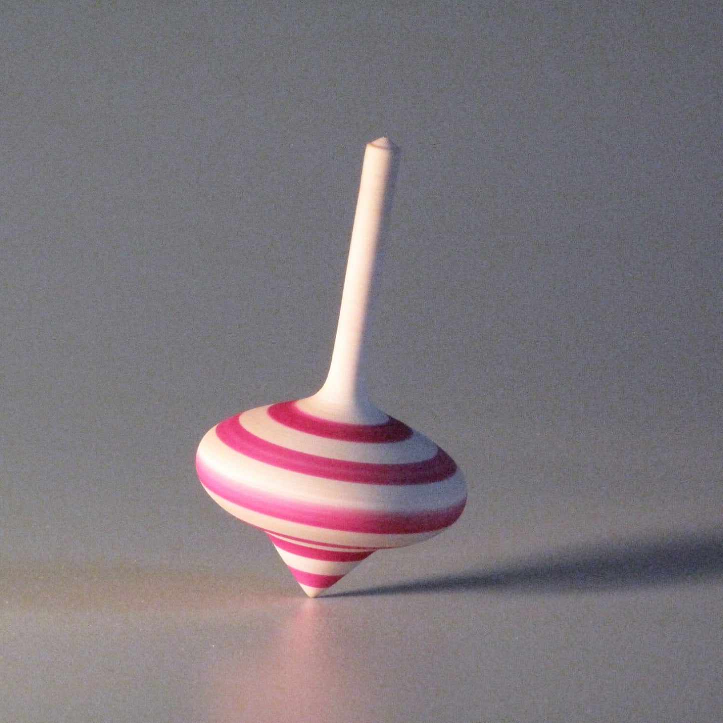 Toy spinning top with pink stripes